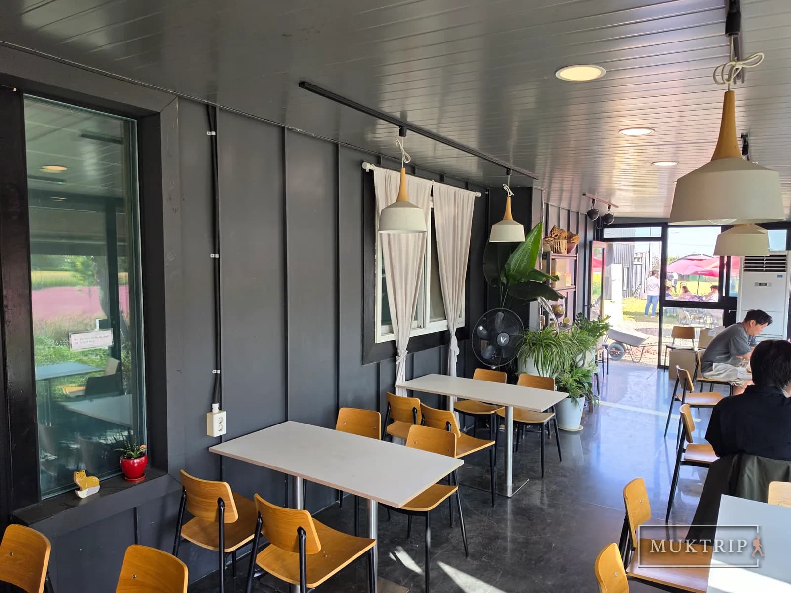 木の椅子と白いテーブルが置かれた居心地のよいカフェの店内