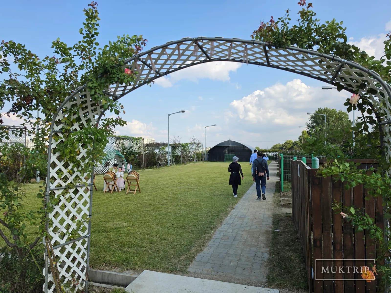 バラの蔓のアーチの向こうに広がる芝生の散策路