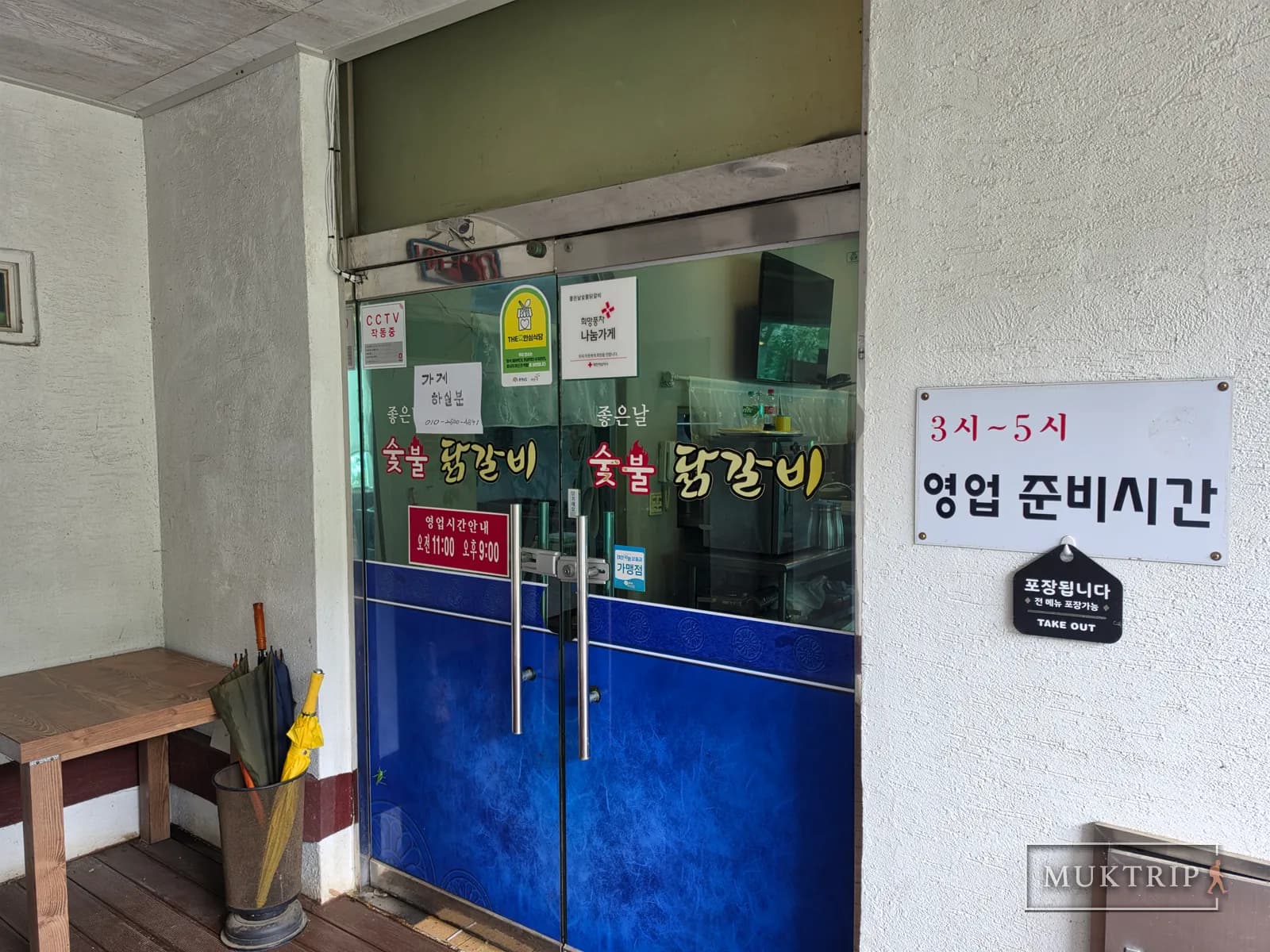 The blue glass entrance door of Joeunnal Sutbul Dakgalbi (Charcoal Dakgalbi) with a business hours sign