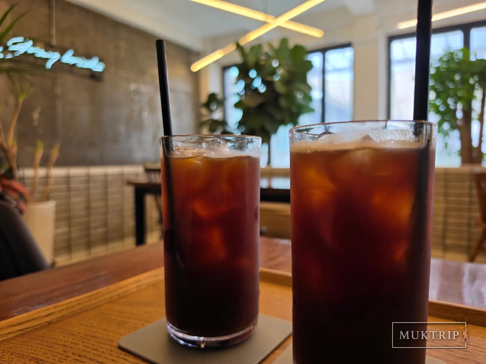 Two iced Americanos full of ice with straws