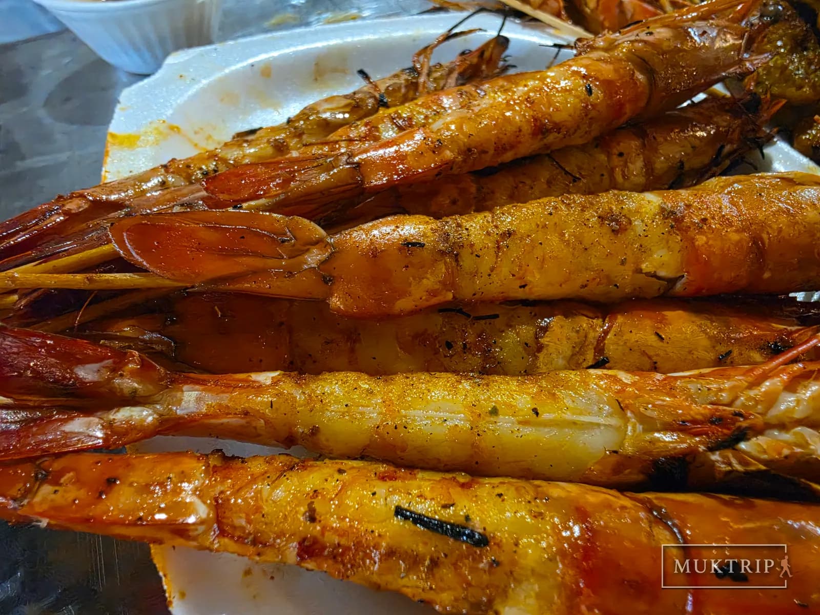Several grilled tiger prawns stacked on top of each other on the grill