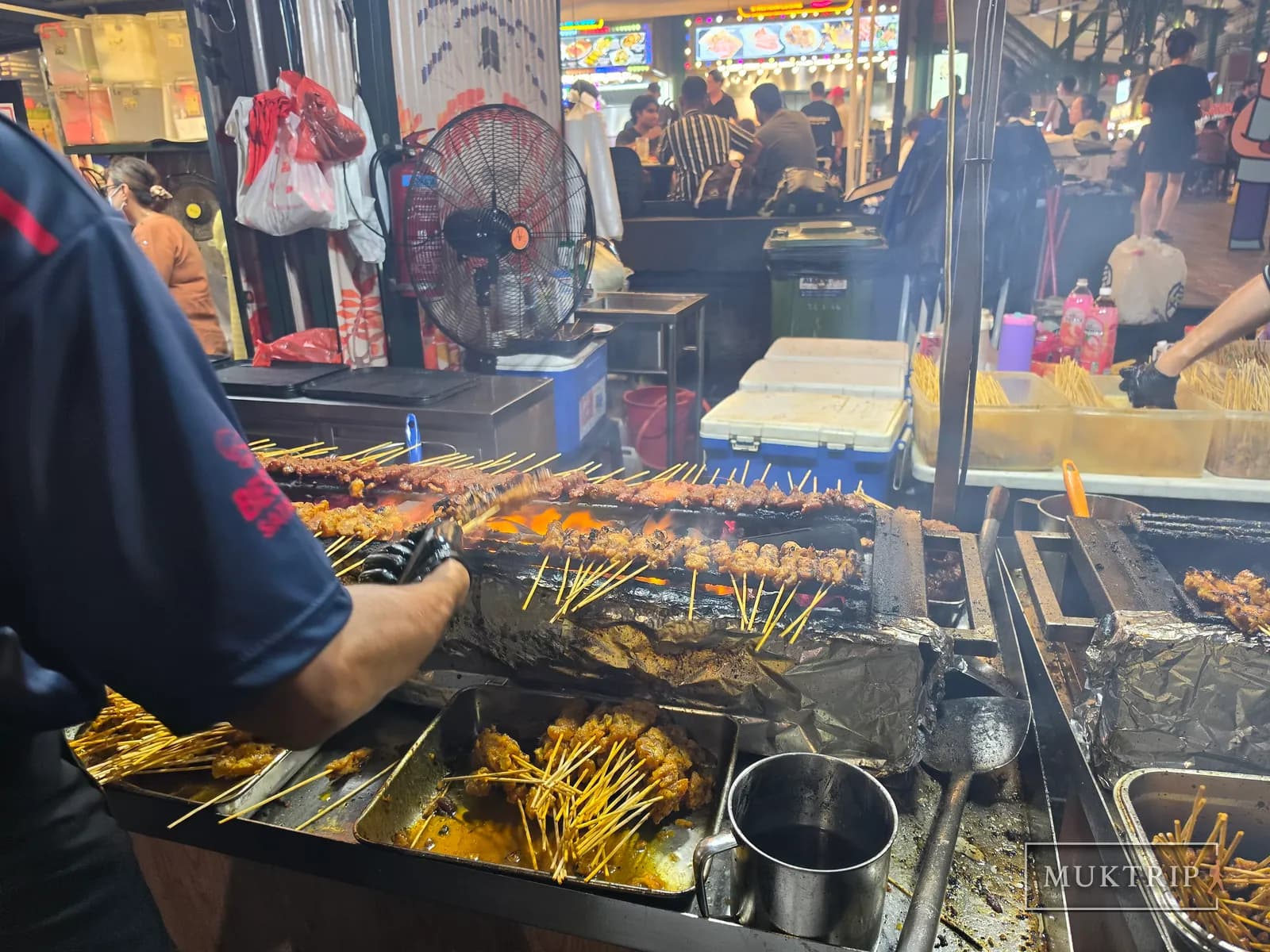 Grilling satay skewers over charcoal at a Lau Pa Sat satay stall
