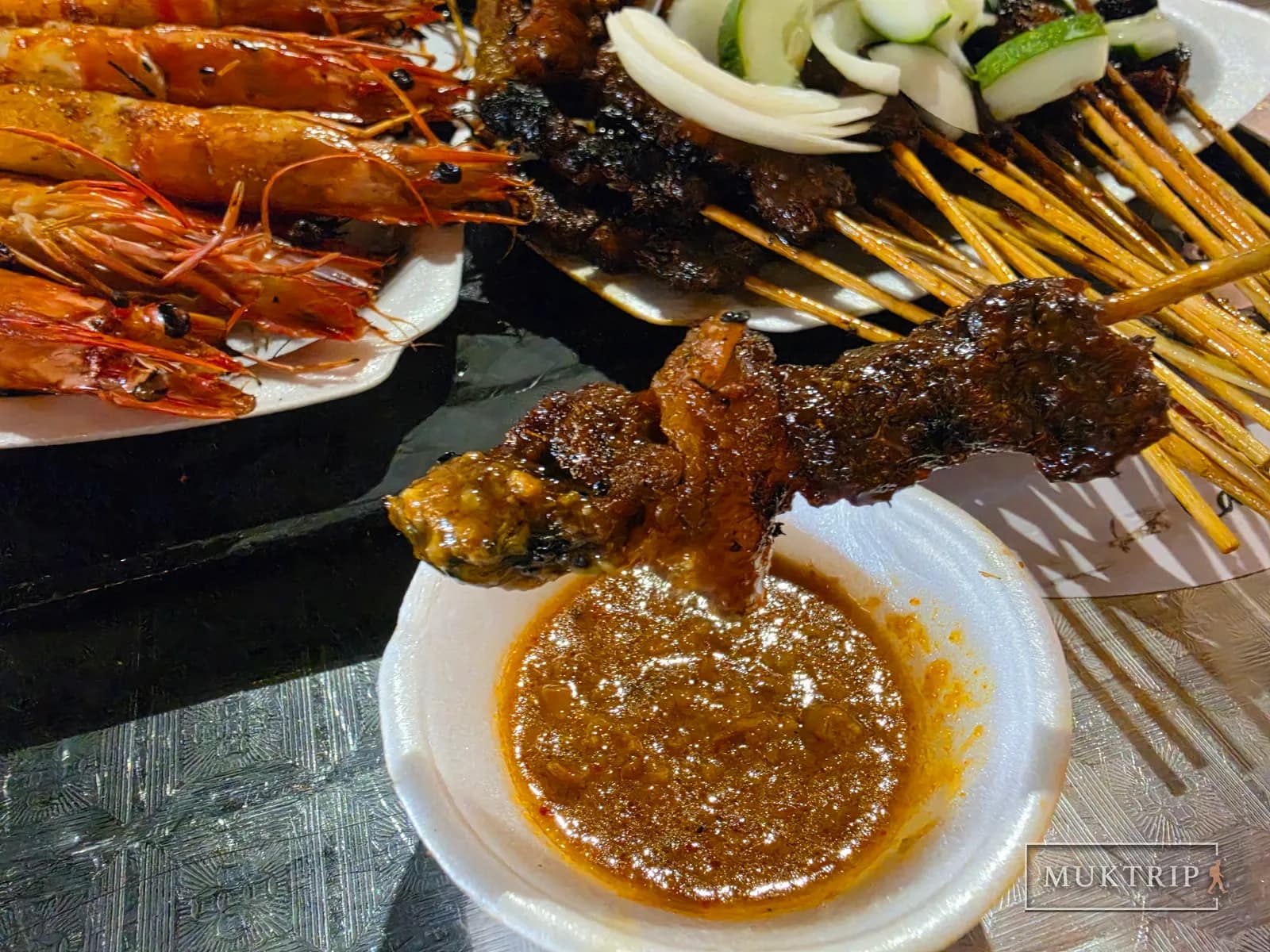 Dipping a satay skewer into sauce