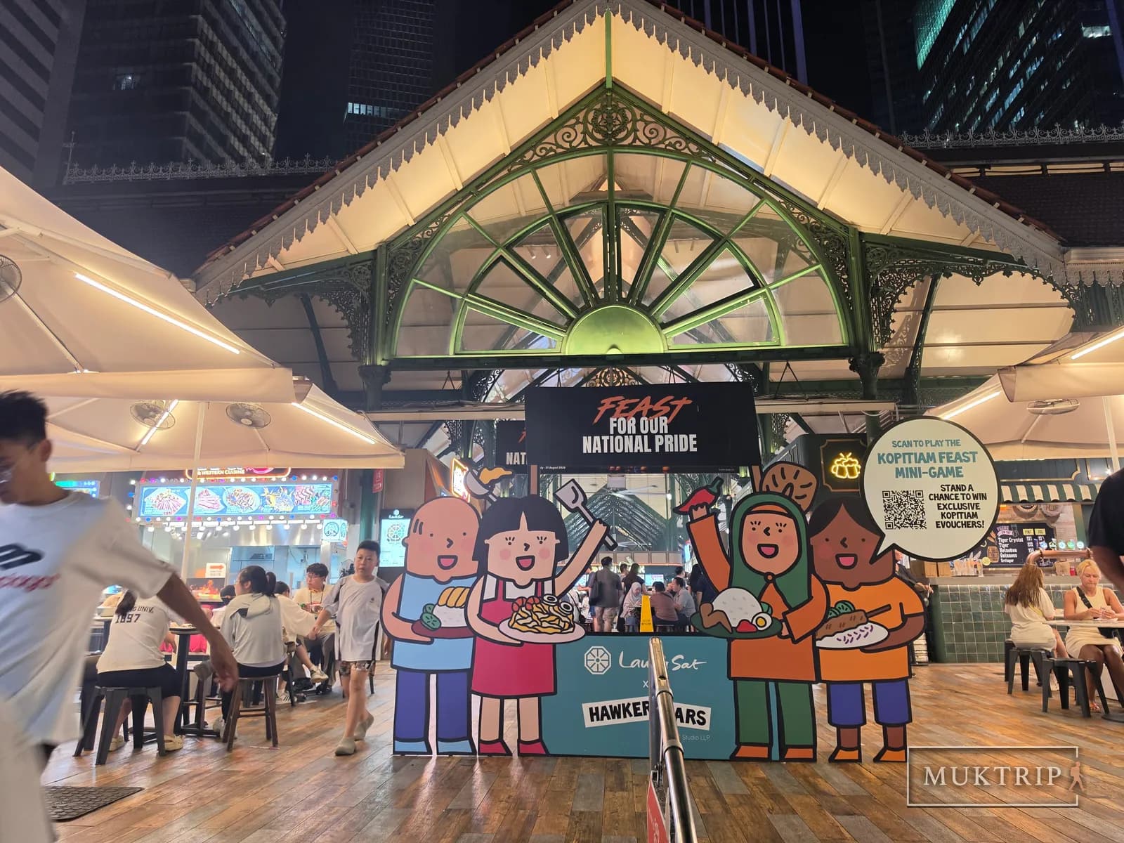 Festival banners and character figures beneath Lau Pa Sat's Victorian-style roof