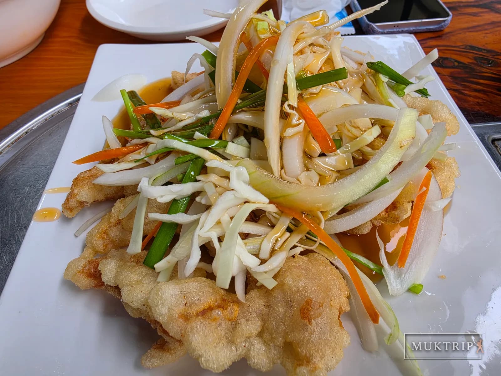 A plate of tangsuyuk topped with julienned vegetables and sauce