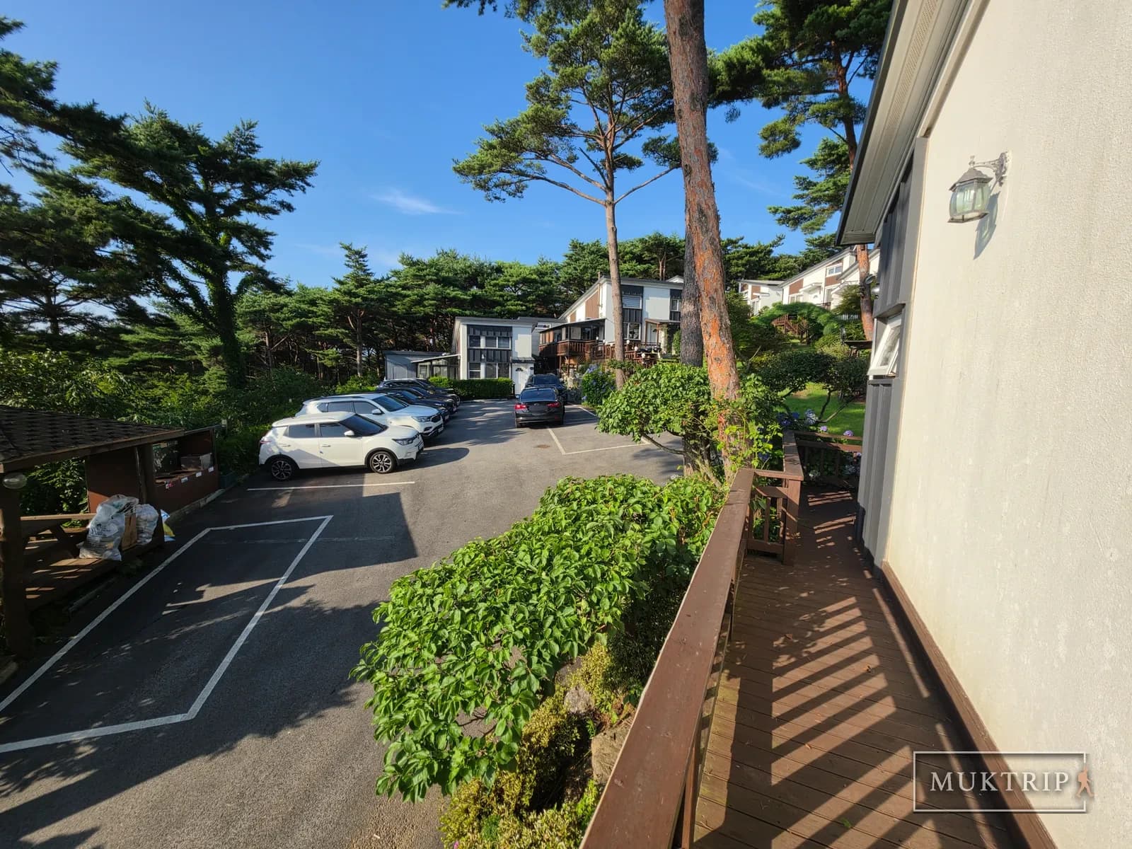 Cars parked in the Ssolmirabell Pension parking lot with a deck extending alongside