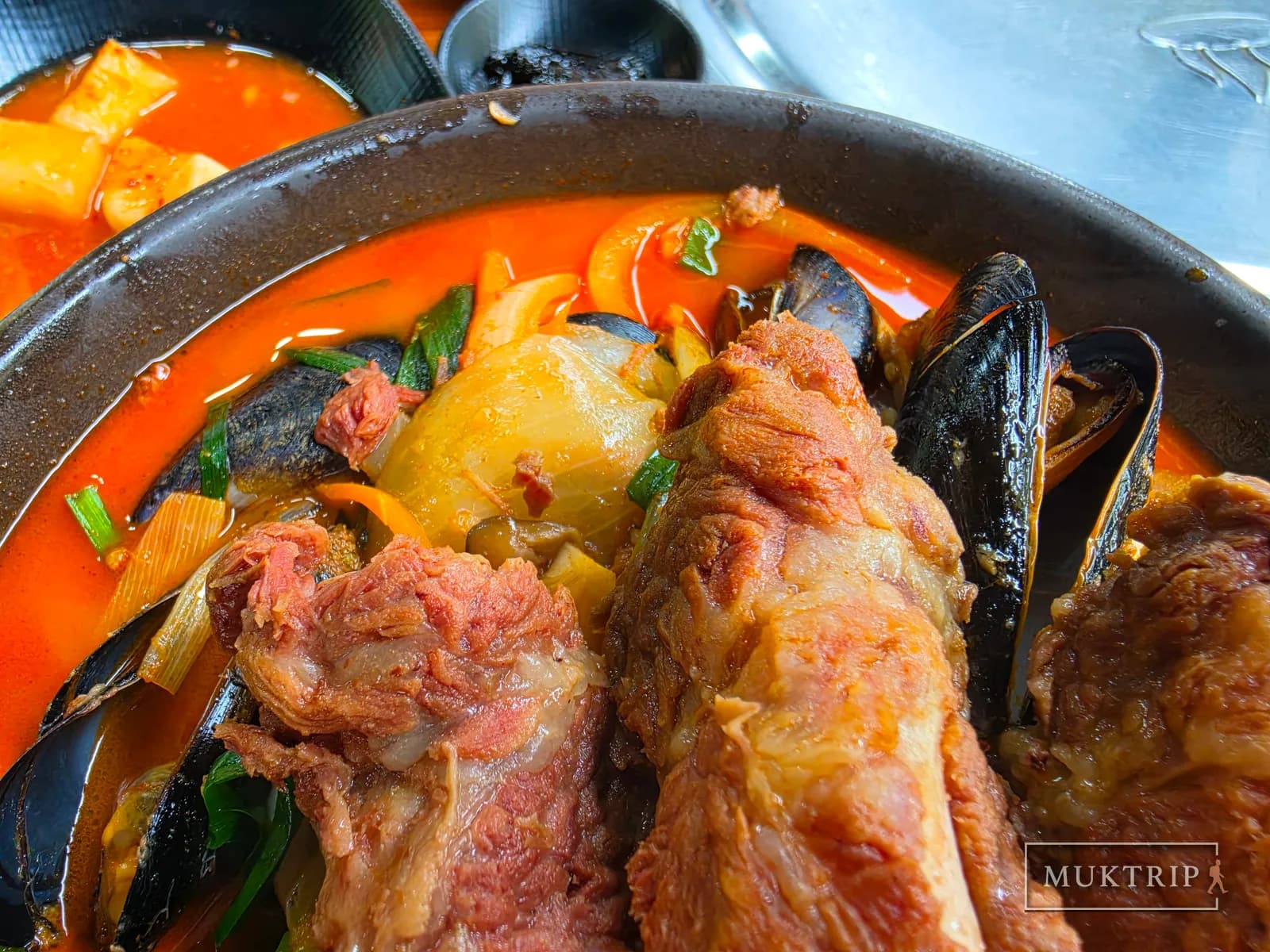 A close-up of jjamppong with ribs, mussels, and green onion