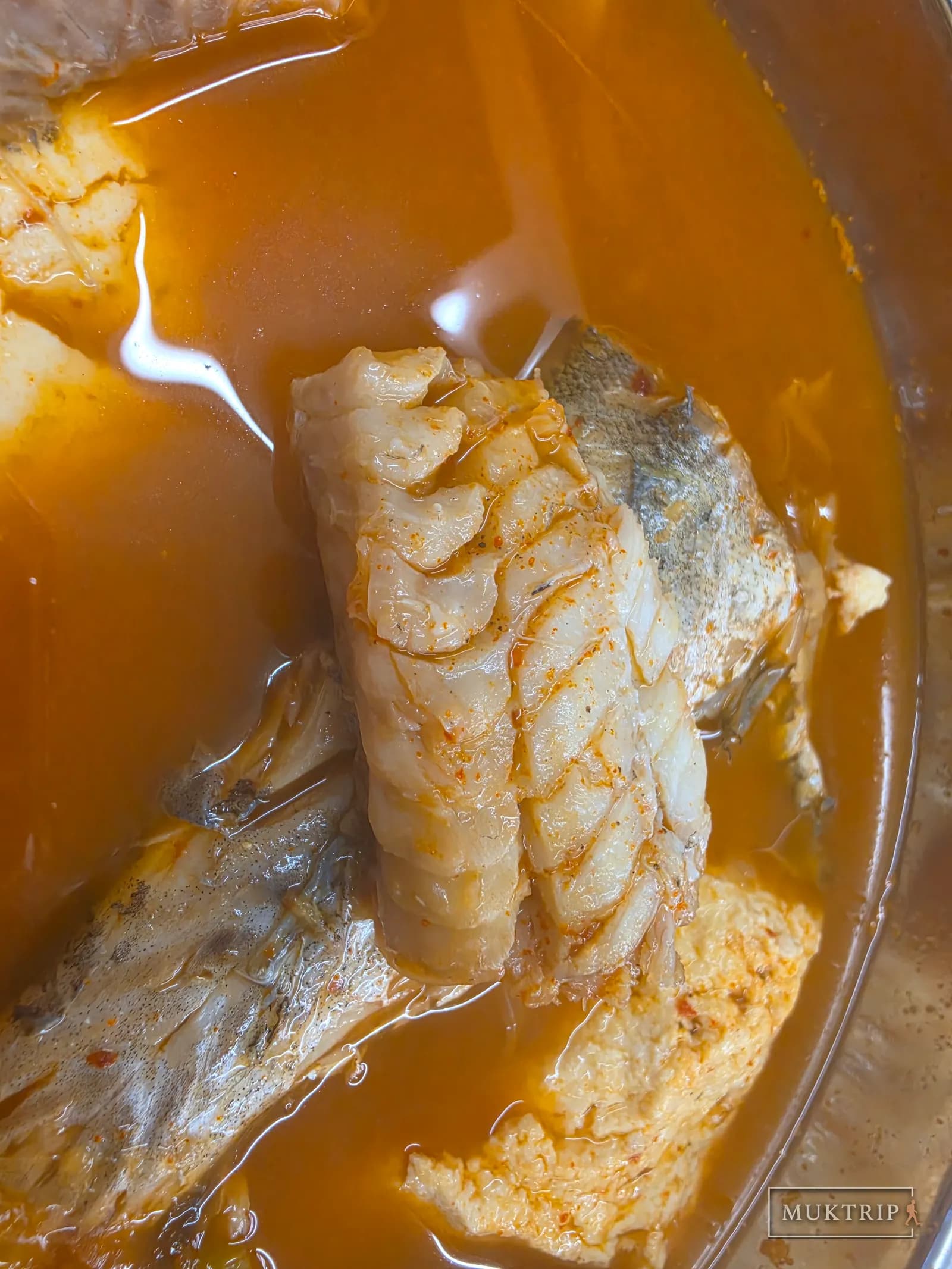 赤いスープに浸ったやわらかな白身魚の身
