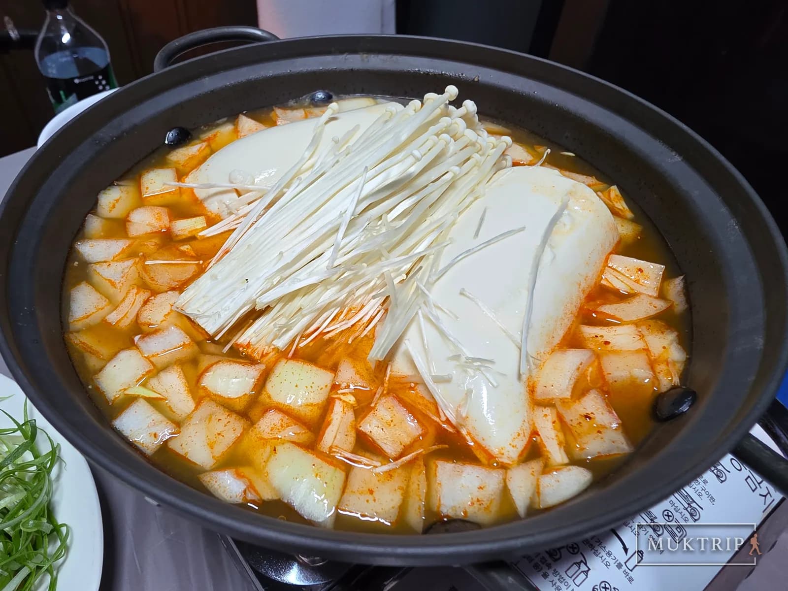 Sundubu-jjigae with soft tofu, onion, and enoki mushrooms