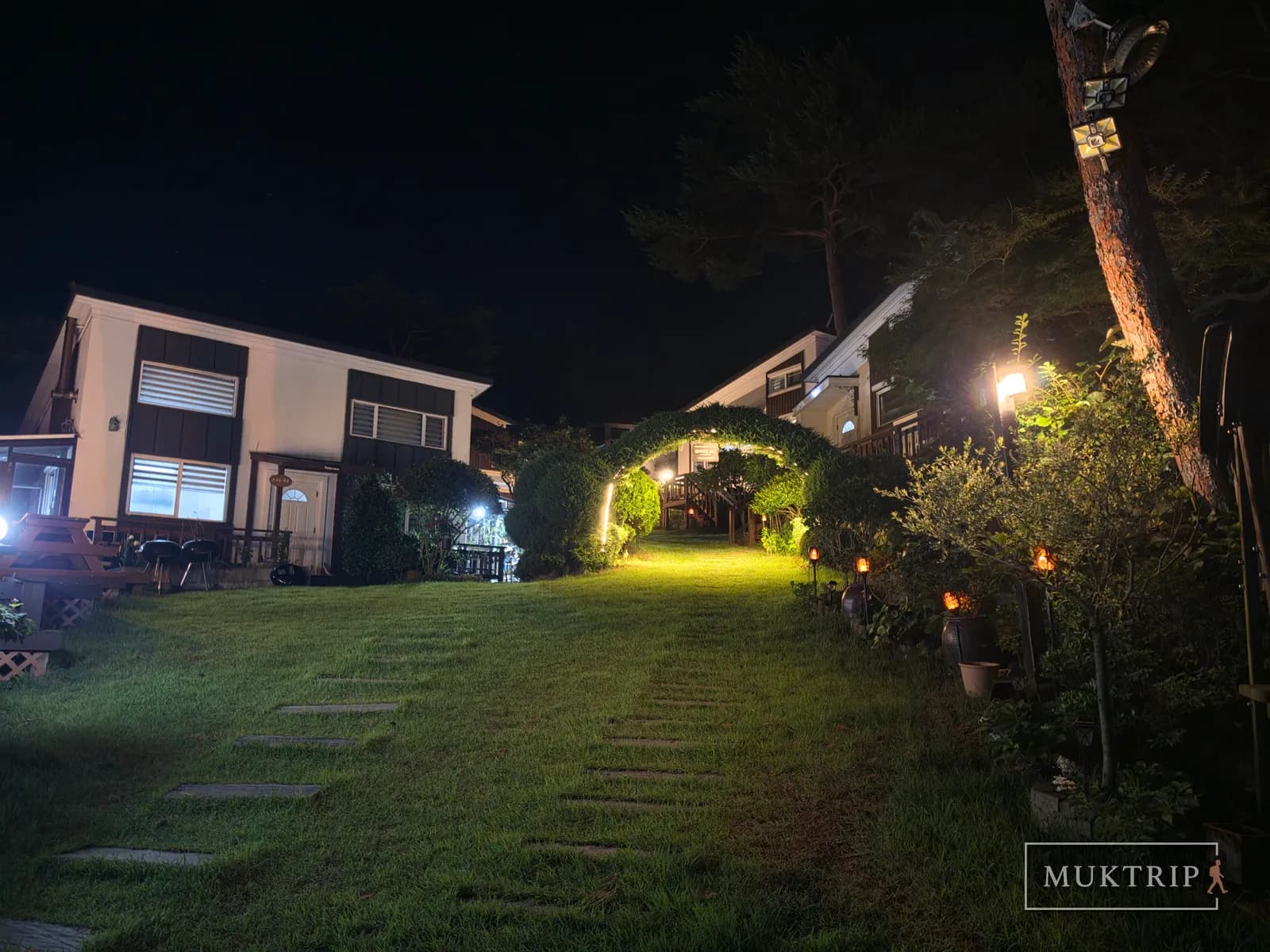 A stepping-stone path and a green arch in the yard of Ssolmirabell Pension at night