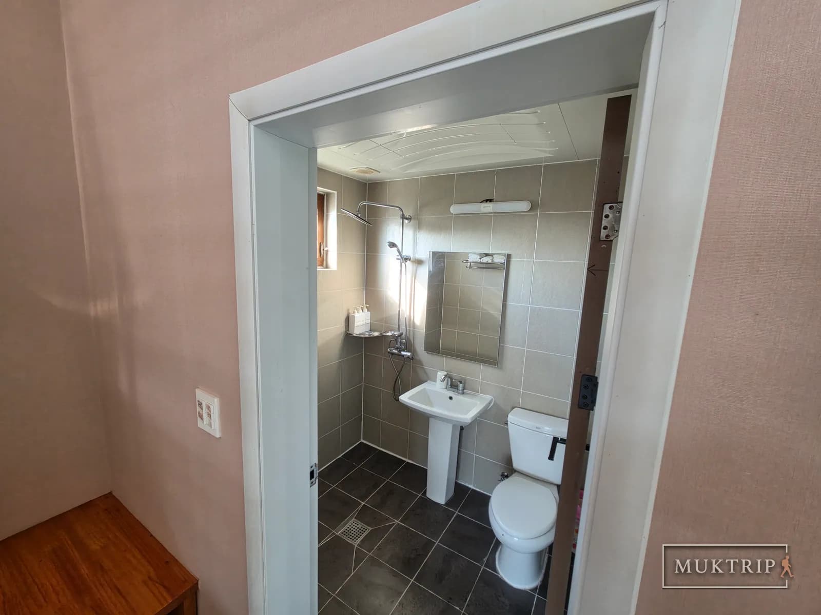 A shower booth, sink, and toilet in a bathroom finished with gray tiles