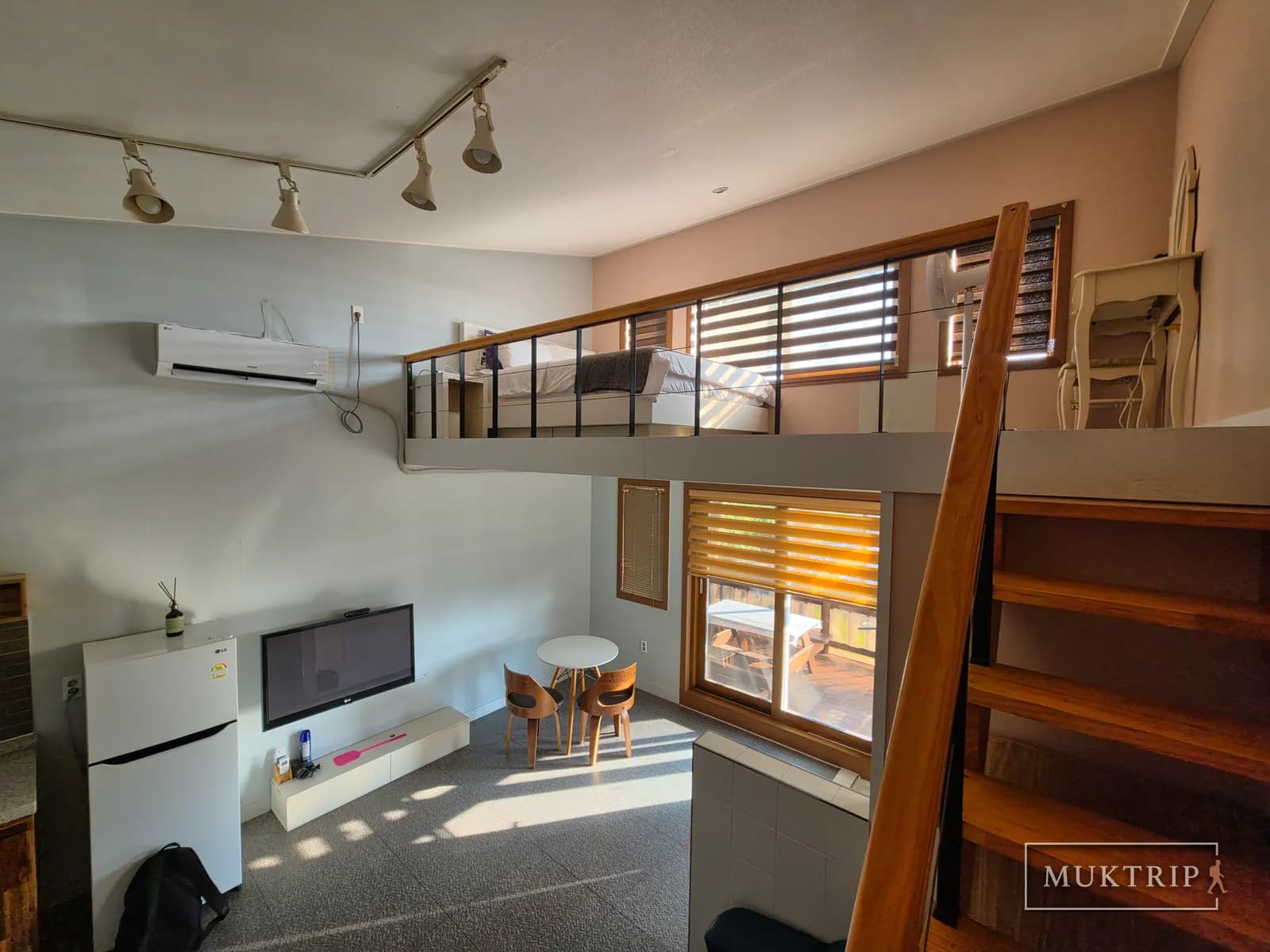 The living room's TV, refrigerator, and table seen from the loft railing