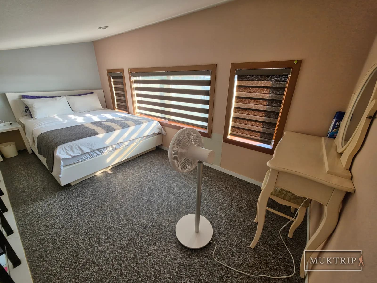 A double bed, fan, and dressing table in the loft bedroom