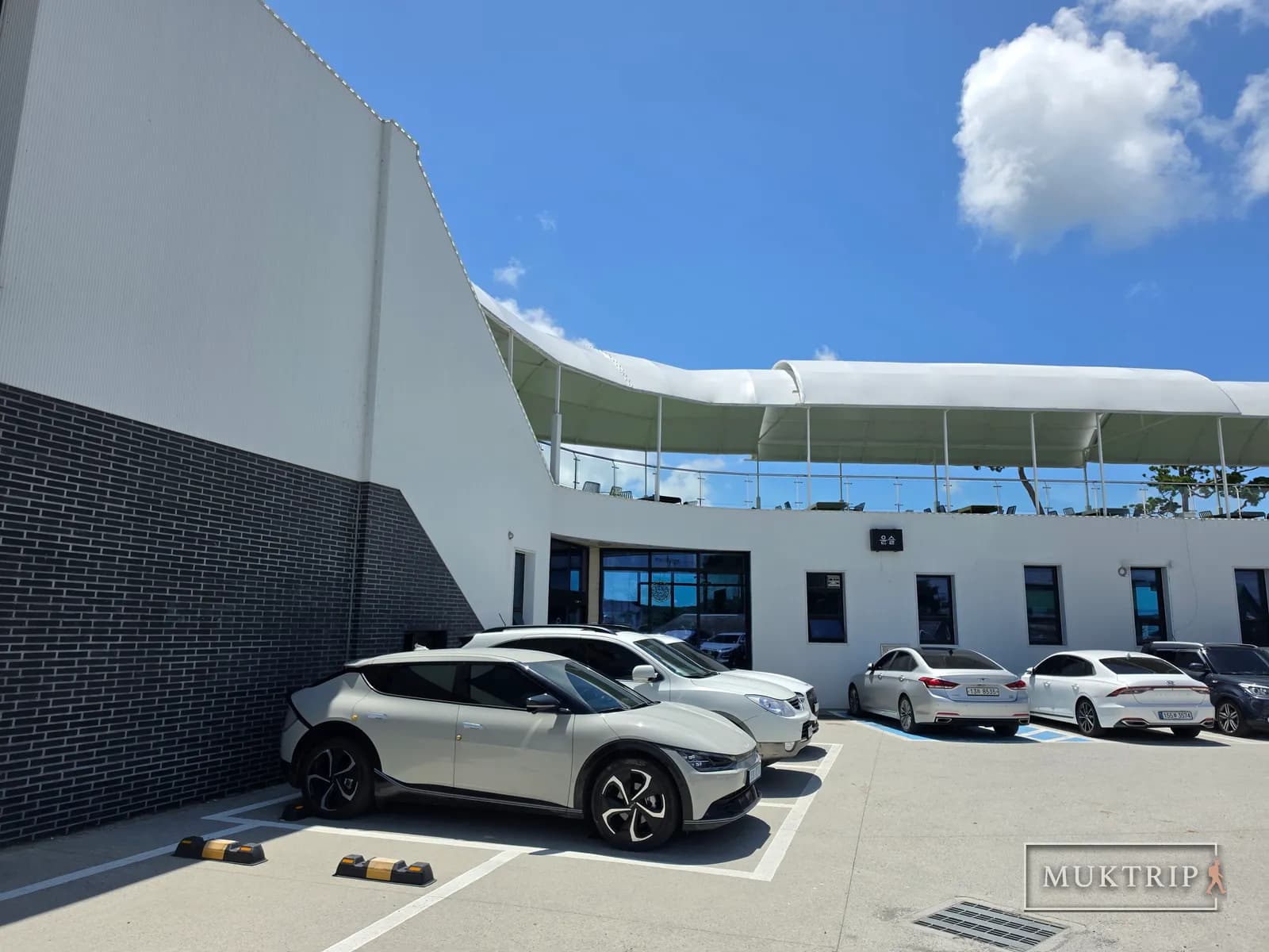 「ユンスル」の看板が掲げられたカフェの建物と前の駐車場に並ぶ車