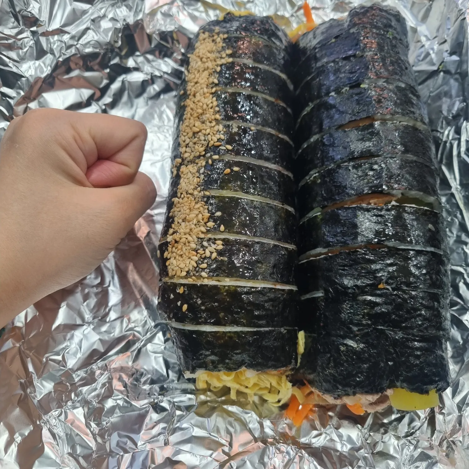 손으로 김밥 크기를 비교하는 모습